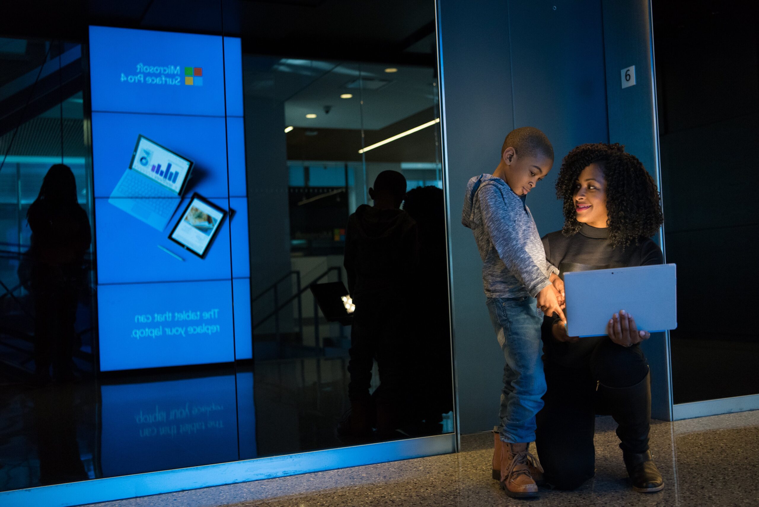 An image of a child and a mother looking at a laptop screen.