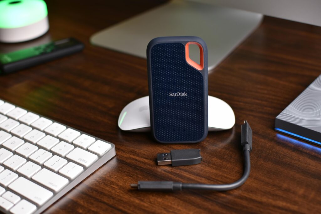An image of a SanDisk external USB drive with two USB cables on a desk used for local backup