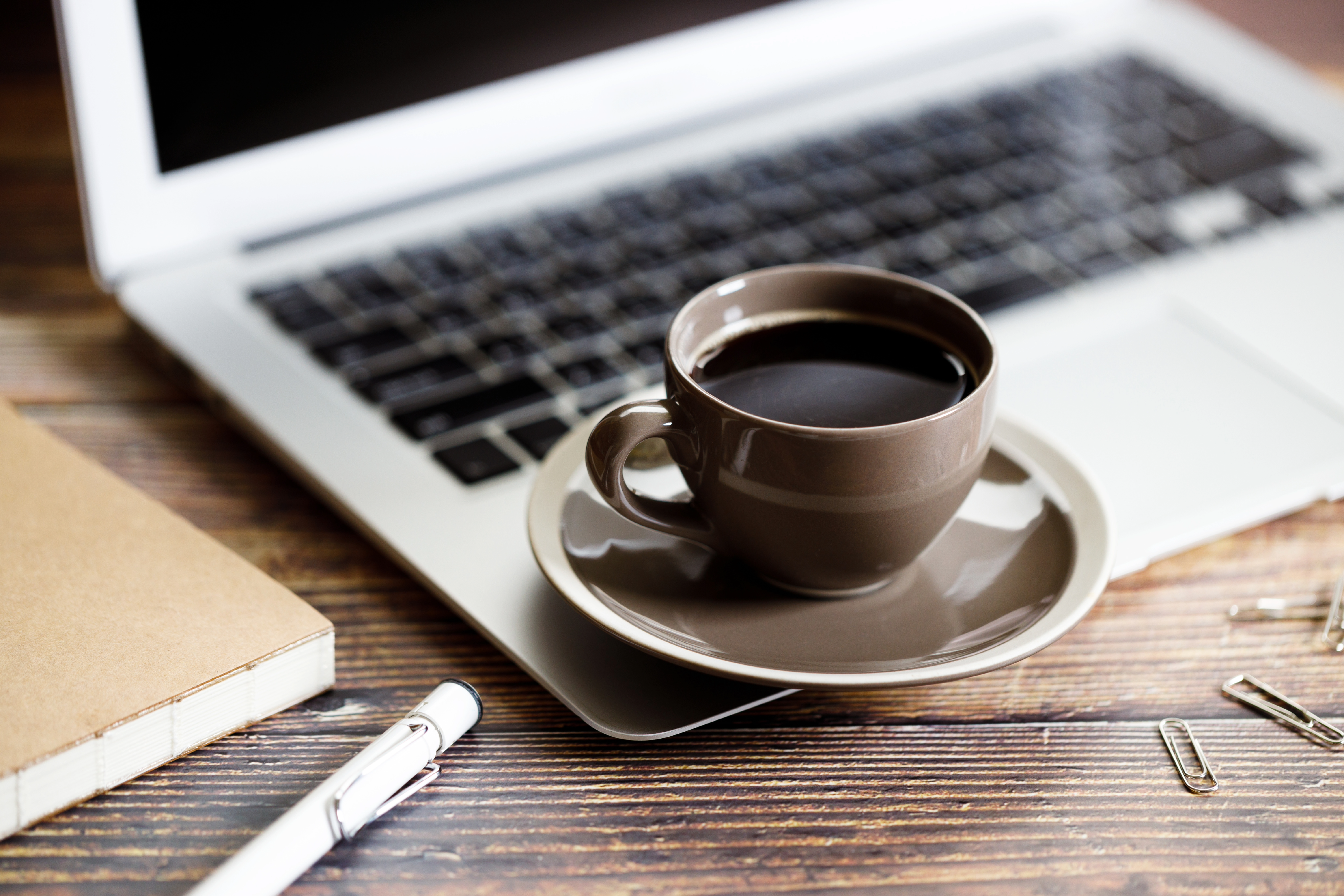 An image showing a cup of coffee placed next to a laptop